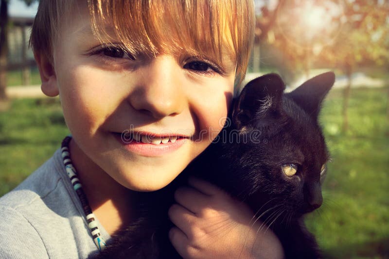Demostraciones del niño con el afecto su gato negro fotos de archivo libres de regalías Demostraciones del niño con el afecto su gato negro fotos de archivo libres de regalías