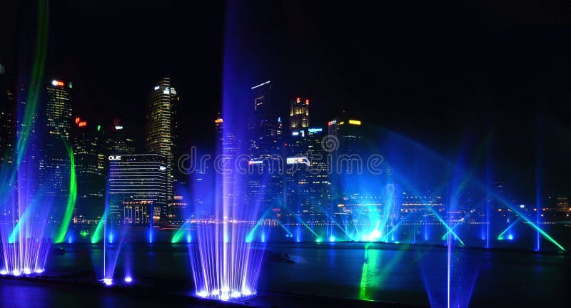 Demostración moderna de la fuente del verde azul en el mar y arquitecturas abstractas y horizonte de la noche en Singapur fotos de archivo Demostración moderna de la fuente del verde azul en el mar y arquitecturas abstractas y horizonte de la noche en Singapur fotos de archivo