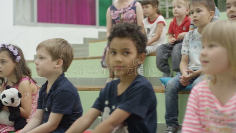 Den afro- amerikanska pojken sitter på trappa mellan Caucasian barn