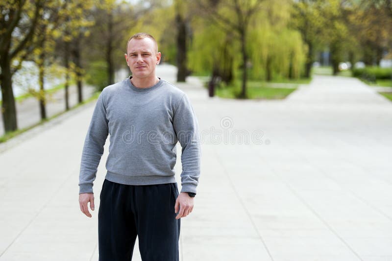 Den aktiva mannen med den idrotts- kroppen, övar utomhus- parkerar in Färdig blick fotografering för bildbyråer Den aktiva mannen med den idrotts- kroppen, övar utomhus- parkerar in Färdig blick fotografering för bildbyråer