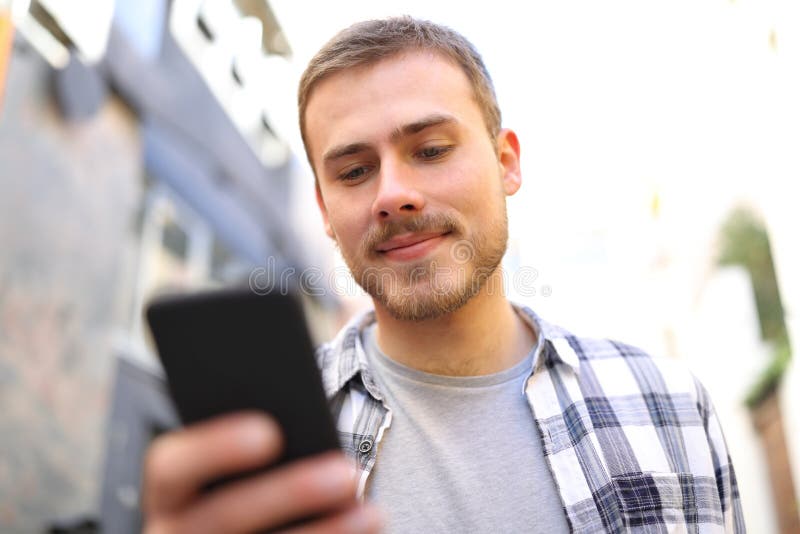 Den allvarliga mannen går genom att använda den smarta telefonen i gatan arkivfoto Den allvarliga mannen går genom att använda den smarta telefonen i gatan arkivfoto