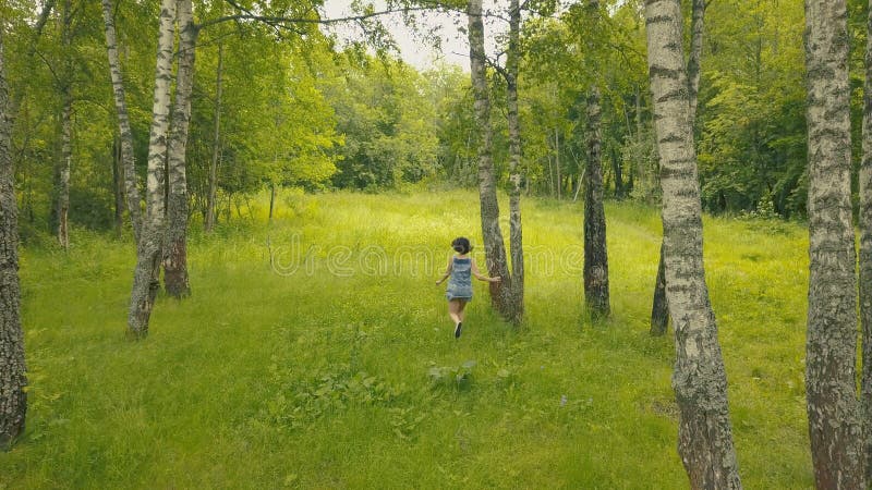 Den Arial sikten som ler den unga kvinnan i skog, följer mig in i skog fotografering för bildbyråer Den Arial sikten som ler den unga kvinnan i skog, följer mig in i skog fotografering för bildbyråer