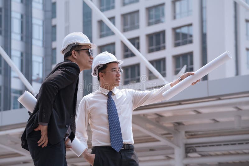 Den asiatiska affärsmannen diskuterar med teknikerarkitektprofessionell w arkivfoton Den asiatiska affärsmannen diskuterar med teknikerarkitektprofessionell w arkivfoton