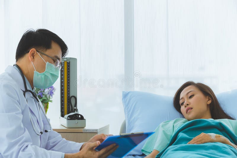Den asiatiska doktorn kontrollerar sjukdomen av den kvinnliga patienten arkivfoton Den asiatiska doktorn kontrollerar sjukdomen av den kvinnliga patienten arkivfoton