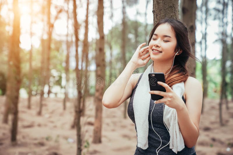 Den asiatiska flickan övar och dricker kallt vatten och lyssnande musik royaltyfri foto Den asiatiska flickan övar och dricker kallt vatten och lyssnande musik royaltyfri foto