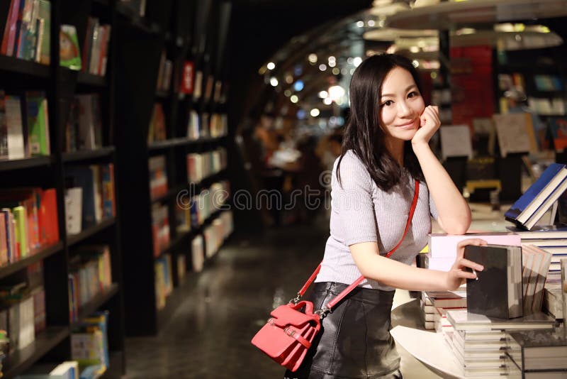 Den asiatiska kinesiska härliga nätta unga gulliga kvinnaflickastudenten Teenager läste boken i bokhandelarkivleende spenderar he royaltyfri fotografi