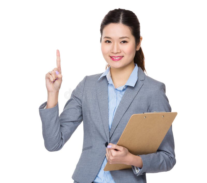 Den asiatiska unga affärskvinnan bär med clipbaord och fingrar punkt