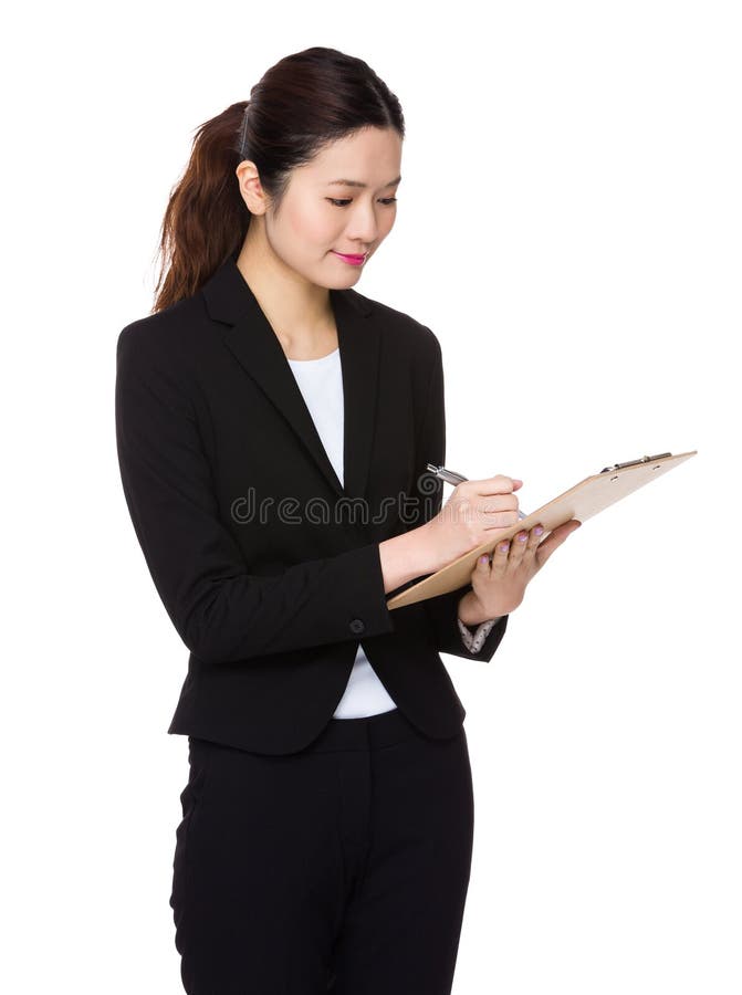 Den asiatiska unga affärskvinnan tar anmärkningen på skrivplattan