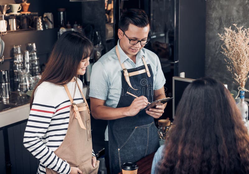 Den Asien Barista uppassaren tar beställning från kund i coffee shop, två royaltyfri foto Den Asien Barista uppassaren tar beställning från kund i coffee shop, två royaltyfri foto