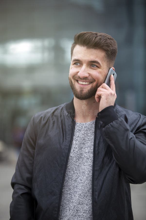 Den attraktiva affärsmannen talar på hans smarta telefon arkivfoton Den attraktiva affärsmannen talar på hans smarta telefon arkivfoton