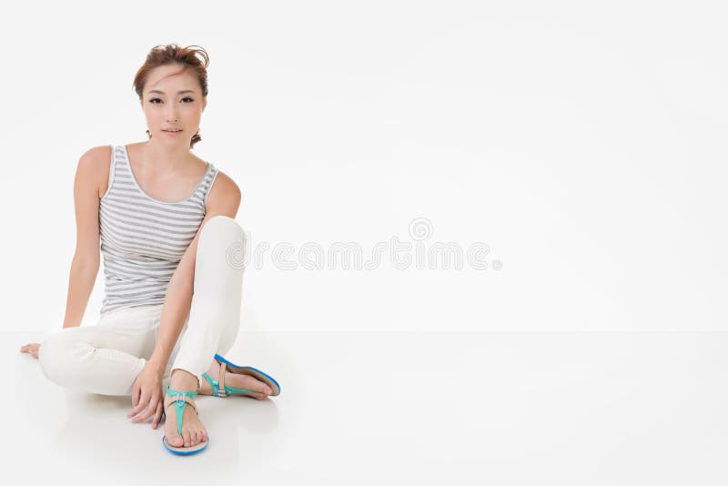 Attractive asian woman sit on ground and looking to the camera. Full length portrait isolated on the white background. Attractive asian woman sit on ground and looking to the camera. Full length portrait isolated on the white background.