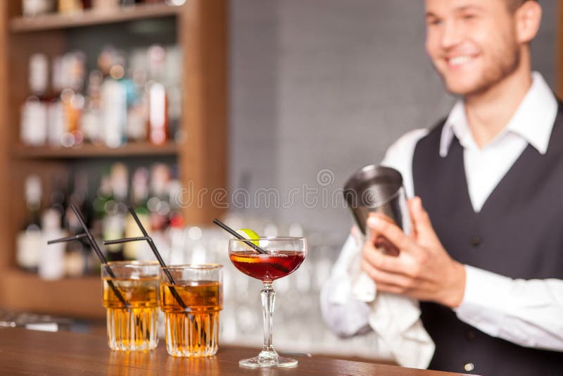 Den attraktiva manliga bartendern skakar drinken i bar arkivfoto Den attraktiva manliga bartendern skakar drinken i bar arkivfoto