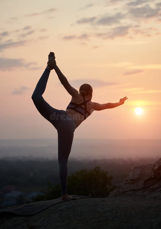 Den attraktiva slanka unga kvinnan som gör yoga, övar utomhus på bakgrund av härlig himmel arkivfoto Den attraktiva slanka unga kvinnan som gör yoga, övar utomhus på bakgrund av härlig himmel arkivfoto