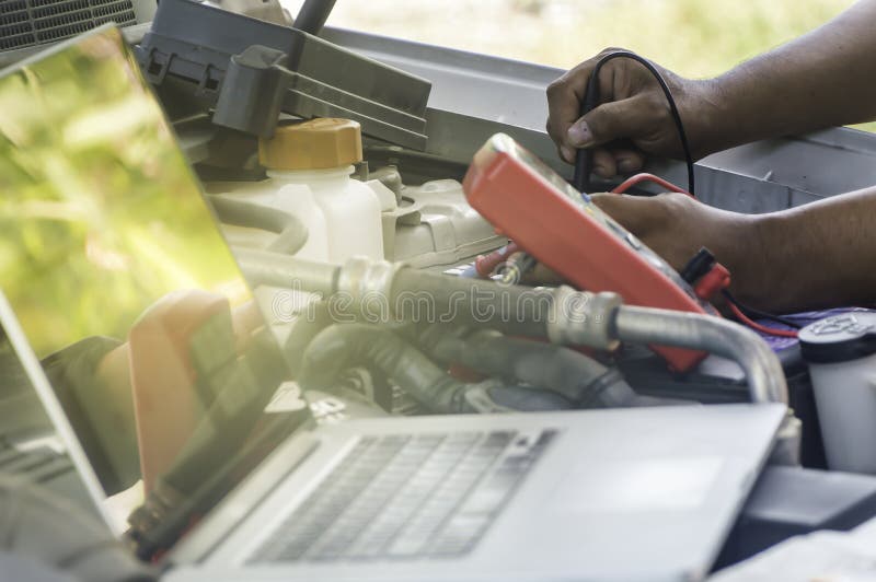 Den auto mekanikern använder en multimetervoltmeter fotografering för bildbyråer Den auto mekanikern använder en multimetervoltmeter fotografering för bildbyråer