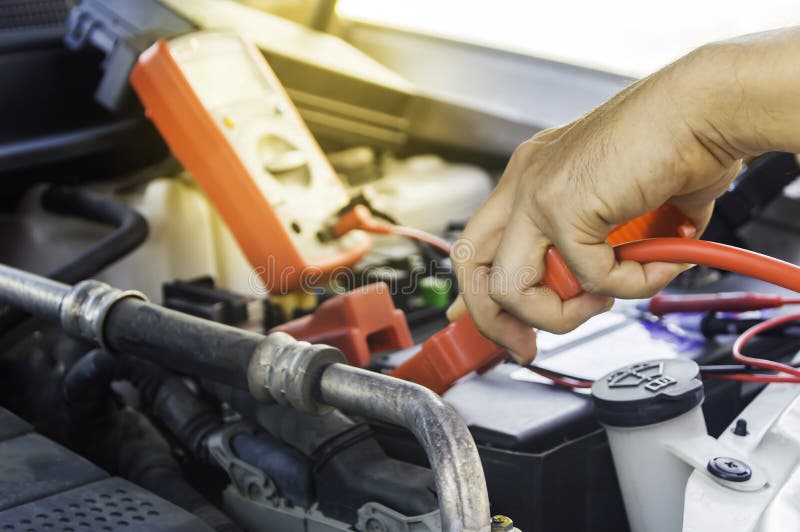 Den auto mekanikern använder ett laddande batteri med elektricitetshoju arkivbilder Den auto mekanikern använder ett laddande batteri med elektricitetshoju arkivbilder