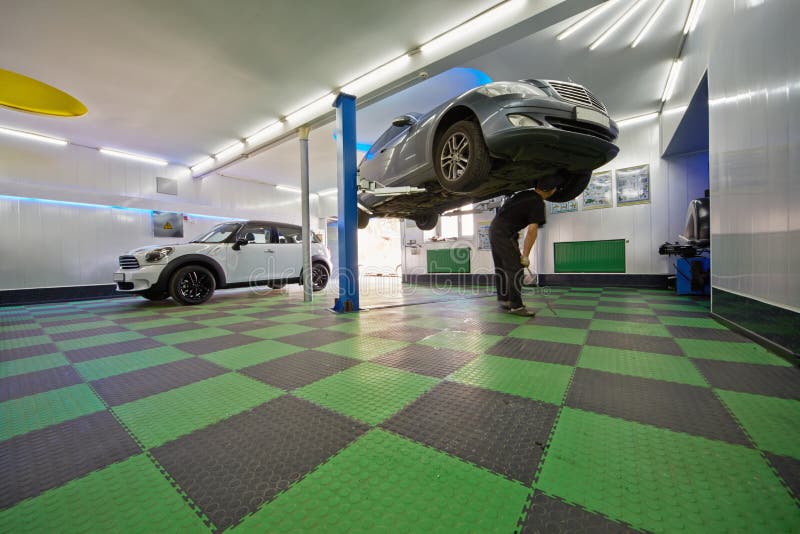 Den automatiska mekanikerarbetaren undersöker bilbotten royaltyfri fotografi Den automatiska mekanikerarbetaren undersöker bilbotten royaltyfri fotografi