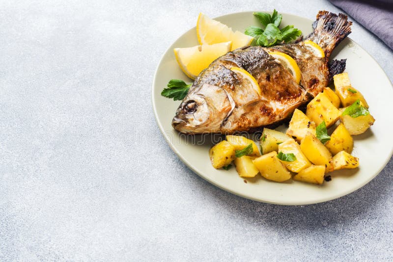 Den bakade fisken kverulerar med citrongräsplaner och potatisar på en platta kopiera avstånd royaltyfria foton Den bakade fisken kverulerar med citrongräsplaner och potatisar på en platta kopiera avstånd royaltyfria foton