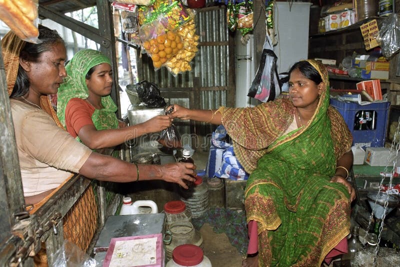 Bangladesh, capital, city Dhaka in the district Mirpur is a female shopkeeper, entrepreneur, selling in her shop, full of colorful wares. Outside are shopping women, one woman buys a bag of rice and the other wants to buy a bottle of oil to cook. The women wear colorful traditional clothes, costume, with a headscarf. In the shop, lying or hanging foods, food or goods such as candy and soda. The female shopkeeper is a small independent. Bangladesh, capital, city Dhaka in the district Mirpur is a female shopkeeper, entrepreneur, selling in her shop, full of colorful wares. Outside are shopping women, one woman buys a bag of rice and the other wants to buy a bottle of oil to cook. The women wear colorful traditional clothes, costume, with a headscarf. In the shop, lying or hanging foods, food or goods such as candy and soda. The female shopkeeper is a small independent.