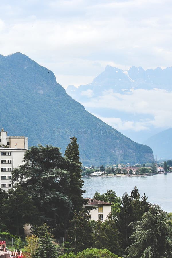 Den berömda staden Montreux i Schweiz på en foggy Day Byggnader efter vackra sjön Genève, schweiziska Alperna i bakgrunden Populä arkivbild Den berömda staden Montreux i Schweiz på en foggy Day Byggnader efter vackra sjön Genève, schweiziska Alperna i bakgrunden Populä arkivbild