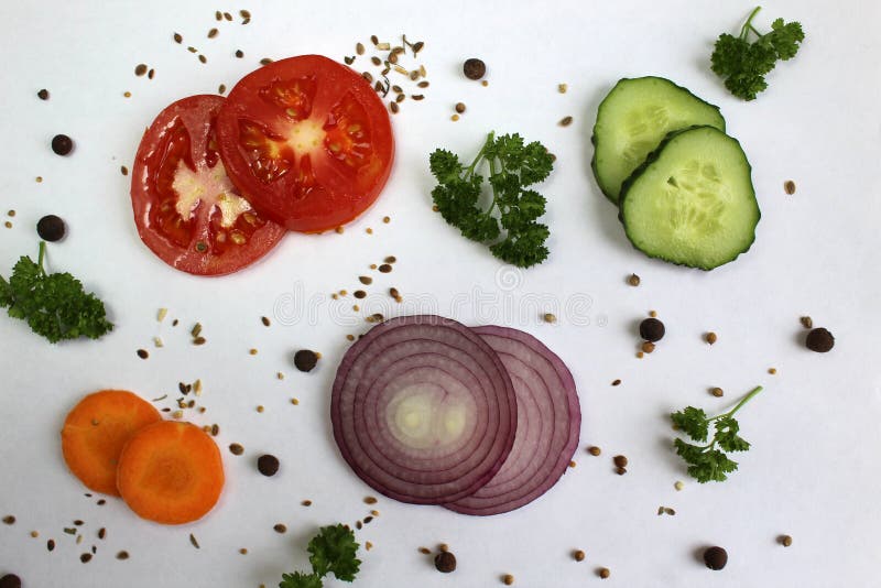 Den bästa sikten, en skiva av tomaten, gurkan och morötter med persiljasidor och lökar ligger på en vit yttersida arkivbild Den bästa sikten, en skiva av tomaten, gurkan och morötter med persiljasidor och lökar ligger på en vit yttersida arkivbild
