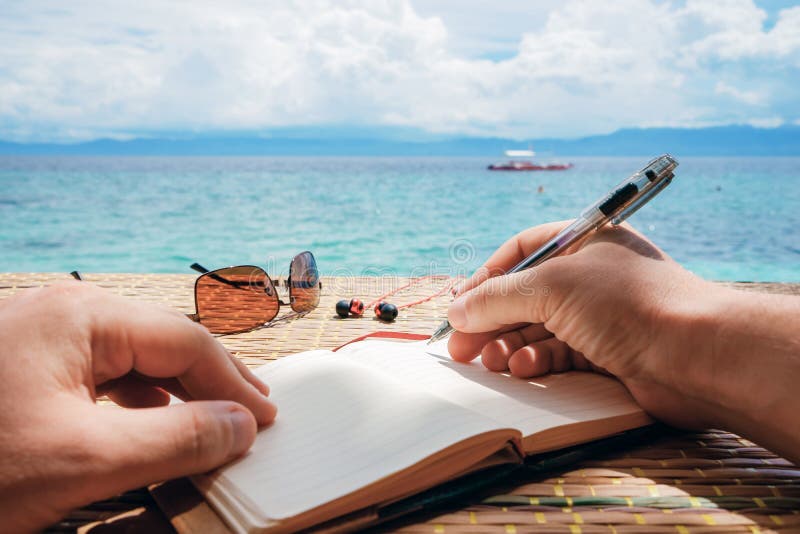Den Caucasian mannen skrivar det simeidé, meddelandet eller brevet i hans notepad vid pennan medan honom sammanträde på stranden royaltyfri fotografi Den Caucasian mannen skrivar det simeidé, meddelandet eller brevet i hans notepad vid pennan medan honom sammanträde på stranden royaltyfri fotografi