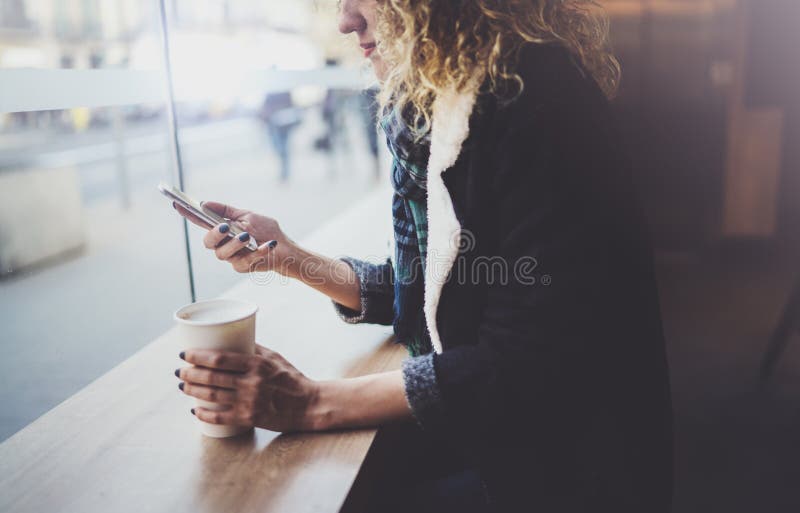Den charmiga kvinnan med det härliga leendet som använder mobiltelefonen under, vilar i coffee shop suddighet bakgrund arkivbild Den charmiga kvinnan med det härliga leendet som använder mobiltelefonen under, vilar i coffee shop suddighet bakgrund arkivbild