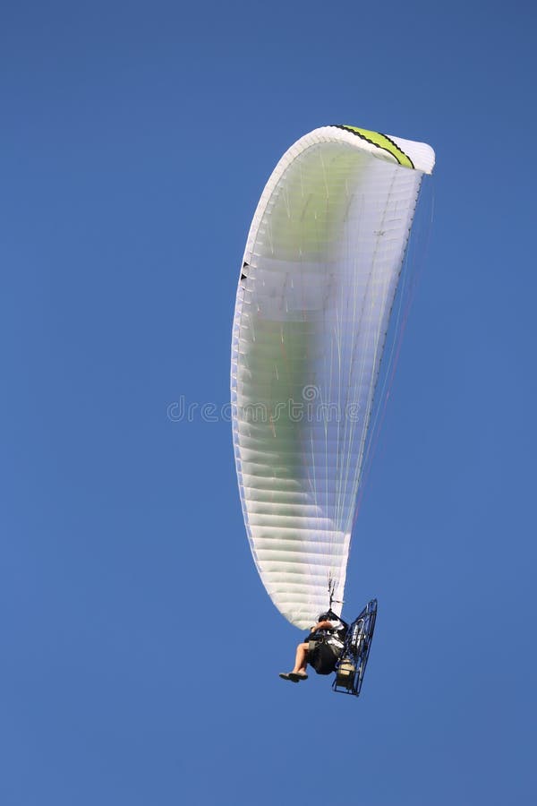 den drev hängningglidflygplanet flyger i den blåa himlen med en person sitter högt arkivbild den drev hängningglidflygplanet flyger i den blåa himlen med en person sitter högt arkivbild