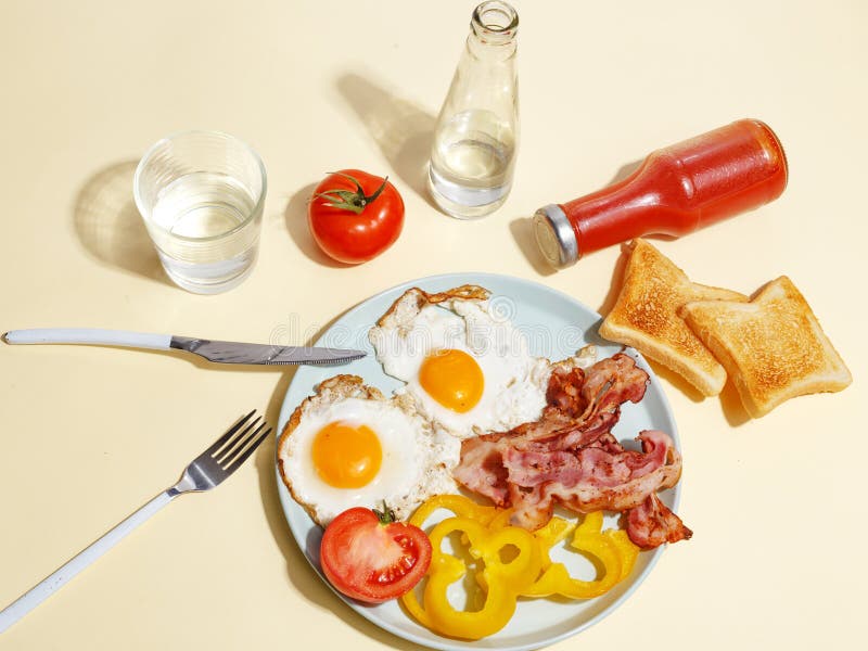 Den enkla frukosten stekte ägget med bacon, spansk peppar och rostat bröd på en platta arkivbild Den enkla frukosten stekte ägget med bacon, spansk peppar och rostat bröd på en platta arkivbild