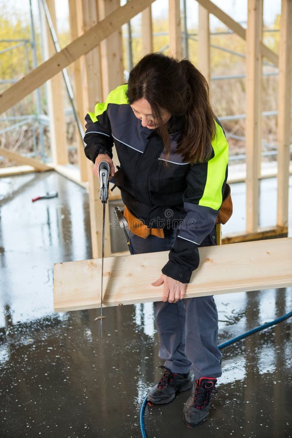Den fulla längden av den kvinnliga snickareCutting Wood With handen såg royaltyfri bild Den fulla längden av den kvinnliga snickareCutting Wood With handen såg royaltyfri bild