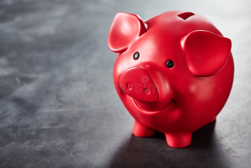 Colorful bright red piggy bank on a slate background with copy space conceptual of finances, savings, success, and retirement. Colorful bright red piggy bank on a slate background with copy space conceptual of finances, savings, success, and retirement
