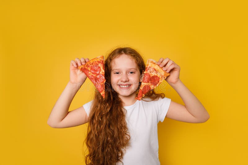 Den galna, smutsiga tjejen håller två pizzasekar nära ögonen och sticker ut sitt tunga royaltyfri fotografi Den galna, smutsiga tjejen håller två pizzasekar nära ögonen och sticker ut sitt tunga royaltyfri fotografi