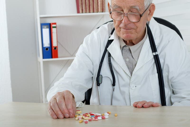 Den gamla doktorn med exponeringsglas studerar lotten av preventivpillerar arkivfoton Den gamla doktorn med exponeringsglas studerar lotten av preventivpillerar arkivfoton