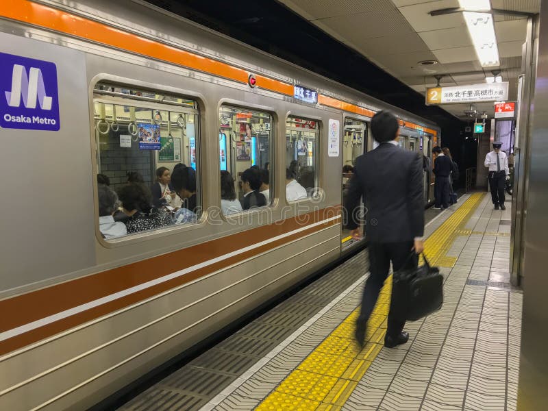 Den gjorda suddig japanska affärsmannen går på vid en drevplattform i Osaka, Japan arkivfoton Den gjorda suddig japanska affärsmannen går på vid en drevplattform i Osaka, Japan arkivfoton