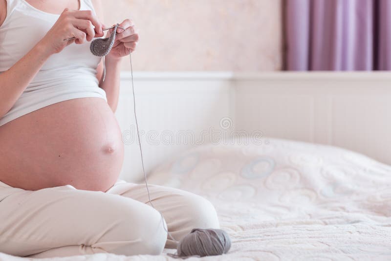 Den gravida unga kvinnan sticker i ett sovrum royaltyfri fotografi Den gravida unga kvinnan sticker i ett sovrum royaltyfri fotografi