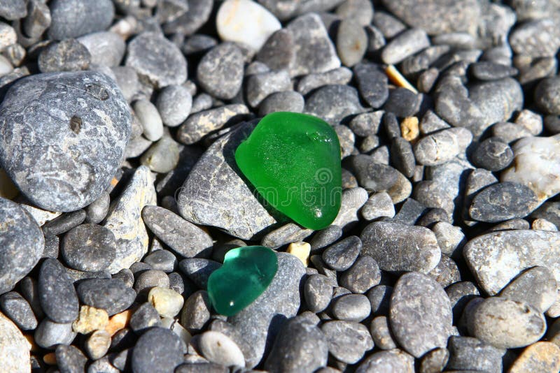 Den gulliga glass skärvan polerad av havet på mörka strandstenar - svarta kiselstenstenar på stranden Foto av naturen royaltyfri bild Den gulliga glass skärvan polerad av havet på mörka strandstenar - svarta kiselstenstenar på stranden Foto av naturen royaltyfri bild
