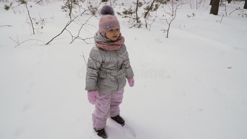 Den gulliga lilla flickan faller ner på snö som är slowmotion