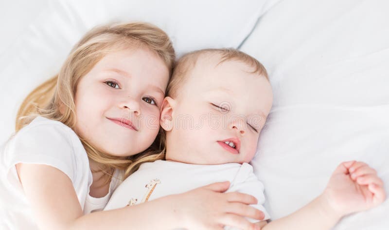 Den gulliga lilla flickan kramar sova behandla som ett barn brodern royaltyfri fotografi