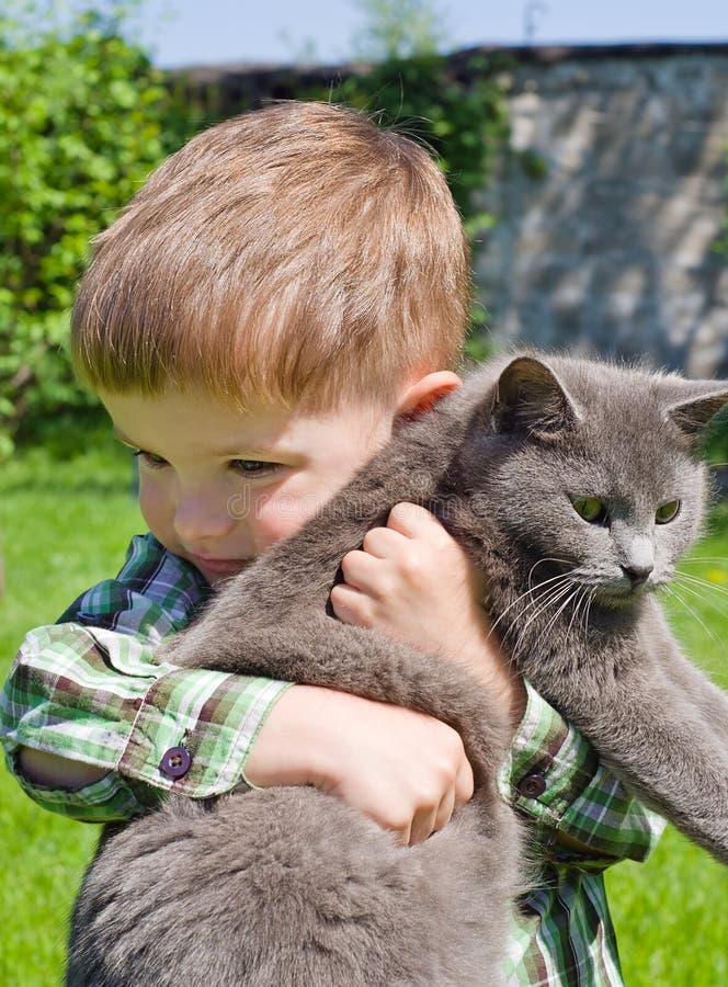 Den gulliga pojken kramar katten royaltyfri fotografi