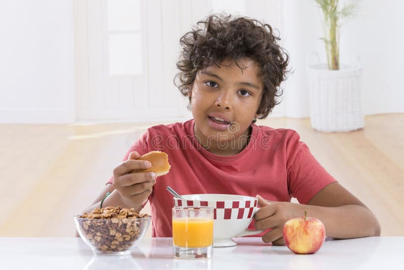 Den gulliga pysen som har frukosten som dricker en stor bunke av, mjölkar hemma i lblueT-tröja arkivfoto Den gulliga pysen som har frukosten som dricker en stor bunke av, mjölkar hemma i lblueT-tröja arkivfoto