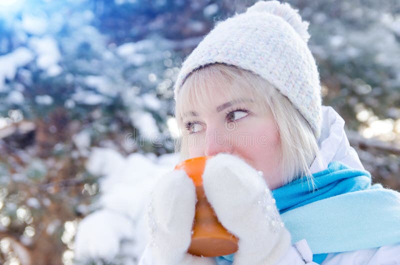 Den härliga blonda flickan i hatt dricker varmt te från koppen arkivfoto Den härliga blonda flickan i hatt dricker varmt te från koppen arkivfoto