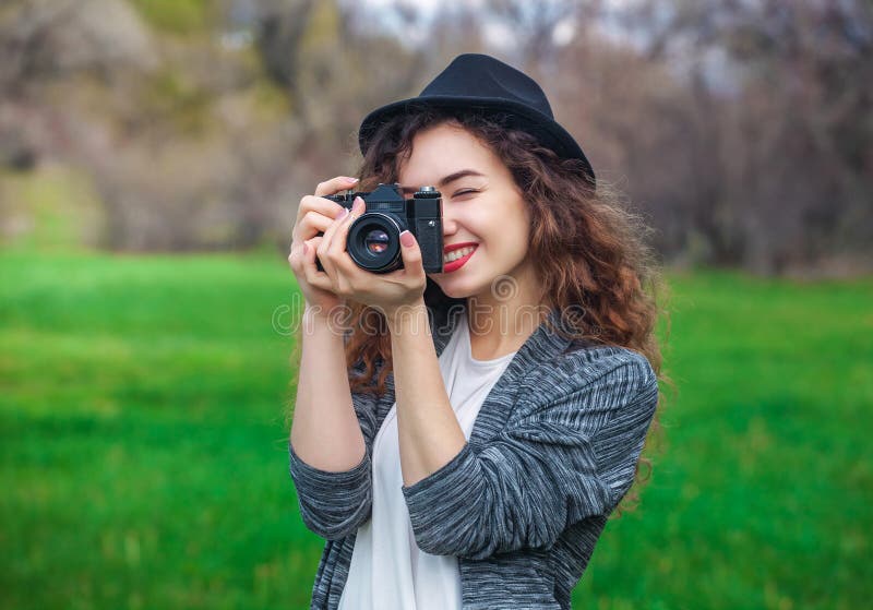 Den härliga flicka-fotografen med lockigt hår som rymmer en gammal kamera och, tar en bild