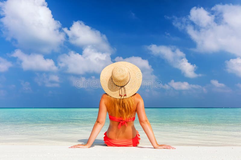 Den härliga unga kvinnan i sunhatsammanträde kopplade av på den tropiska stranden i Maldiverna arkivfoton Den härliga unga kvinnan i sunhatsammanträde kopplade av på den tropiska stranden i Maldiverna arkivfoton