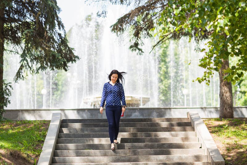 Den härliga unga kvinnan som går i grön sommar, parkerar royaltyfri fotografi Den härliga unga kvinnan som går i grön sommar, parkerar royaltyfri fotografi