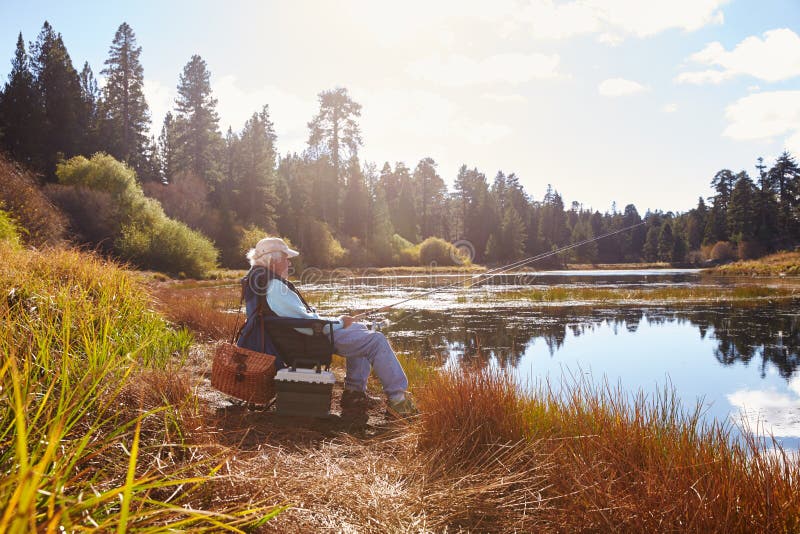 Den höga mannen sitter fiske, den rättframa sjön, Big Bear, Kalifornien royaltyfria foton Den höga mannen sitter fiske, den rättframa sjön, Big Bear, Kalifornien royaltyfria foton