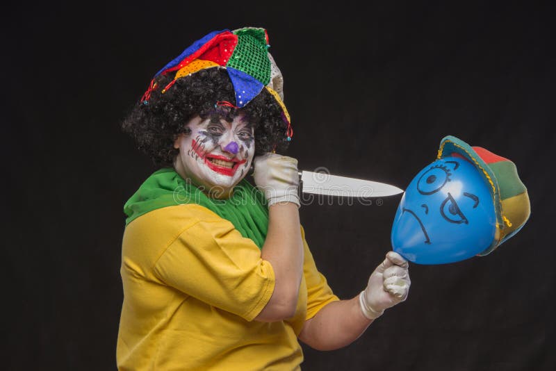 Den ilskna fula clownen önskar att döda en ballong i locket arkivbild Den ilskna fula clownen önskar att döda en ballong i locket arkivbild