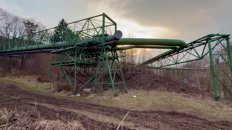 Den industriella infrastrukturen med en grön ledning går ut mot ett Dramatic Sky arkivbilder