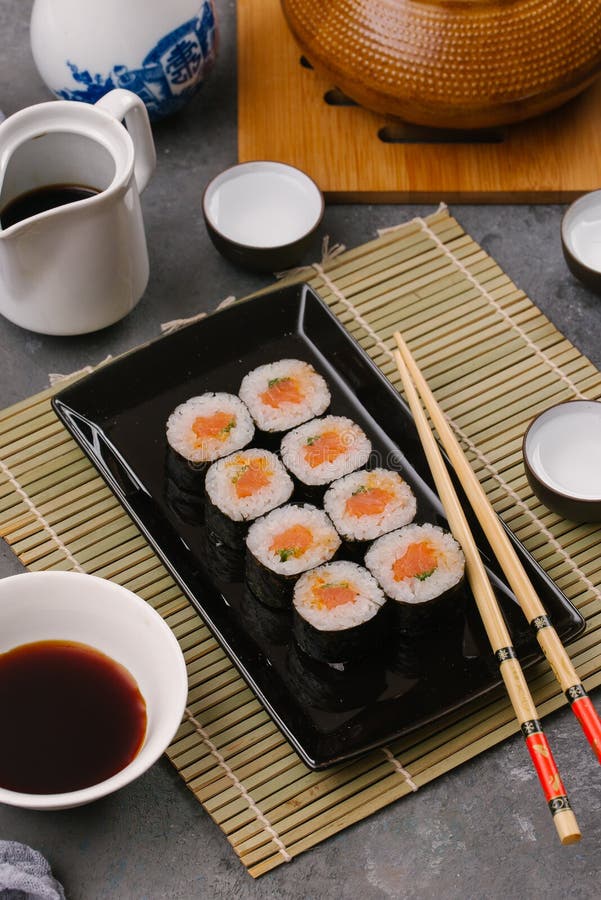 Den japanska restaurangen, sushirulle på svart kritiserar plattan Ställ in för en person med pinnar, ingefäran, sojaböna, den bäs arkivbild Den japanska restaurangen, sushirulle på svart kritiserar plattan Ställ in för en person med pinnar, ingefäran, sojaböna, den bäs arkivbild