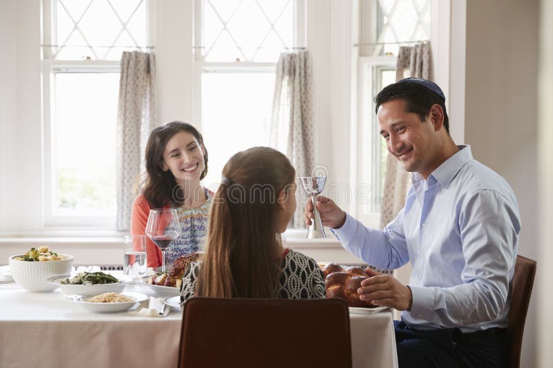 Den judiska mannen som rymmer den kiddish koppen, välsignar hans familj på Shabbat royaltyfria foton Den judiska mannen som rymmer den kiddish koppen, välsignar hans familj på Shabbat royaltyfria foton