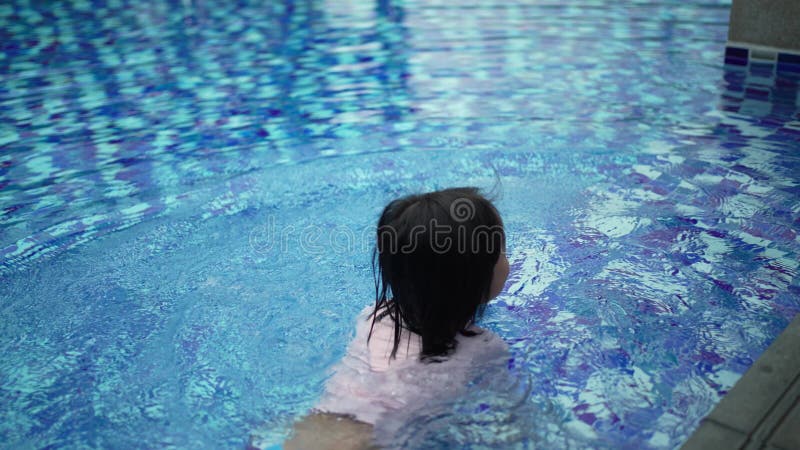 Den kinesiska flickan tar av sig ansiktsmask för att simma i poolen