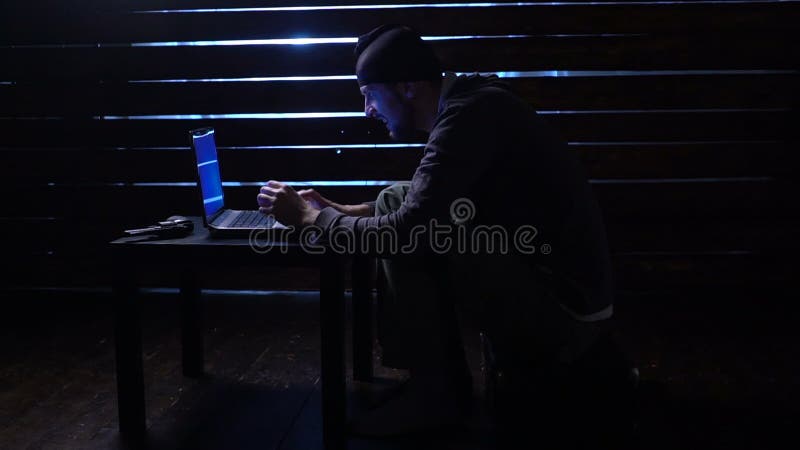 Den komiska roliga en hacker begår en cyberattack med en bärbar dator och ett vapen i hans händer